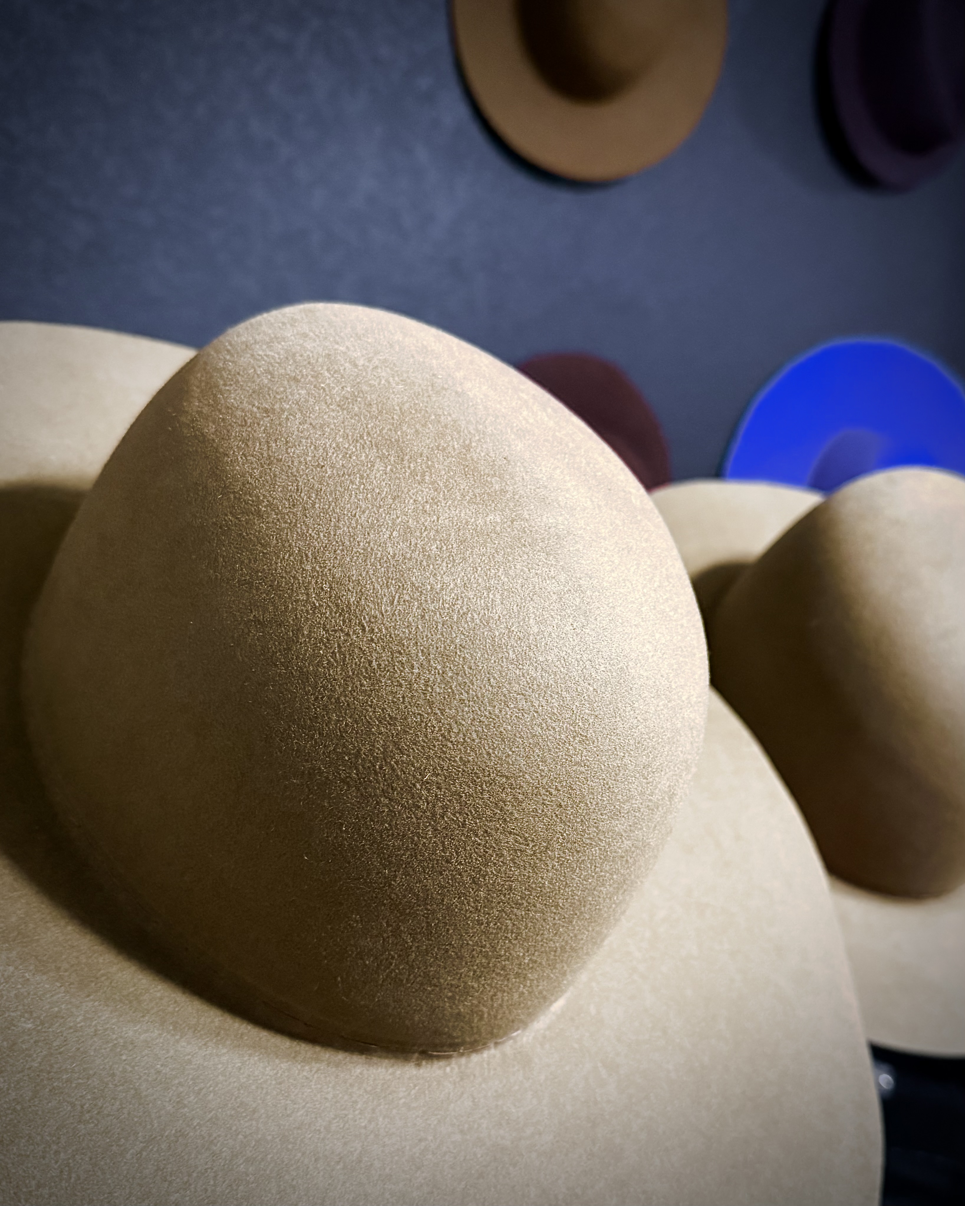 Craft macro — felt nap, blocking, hands and tools shaping a fur-felt hatbody